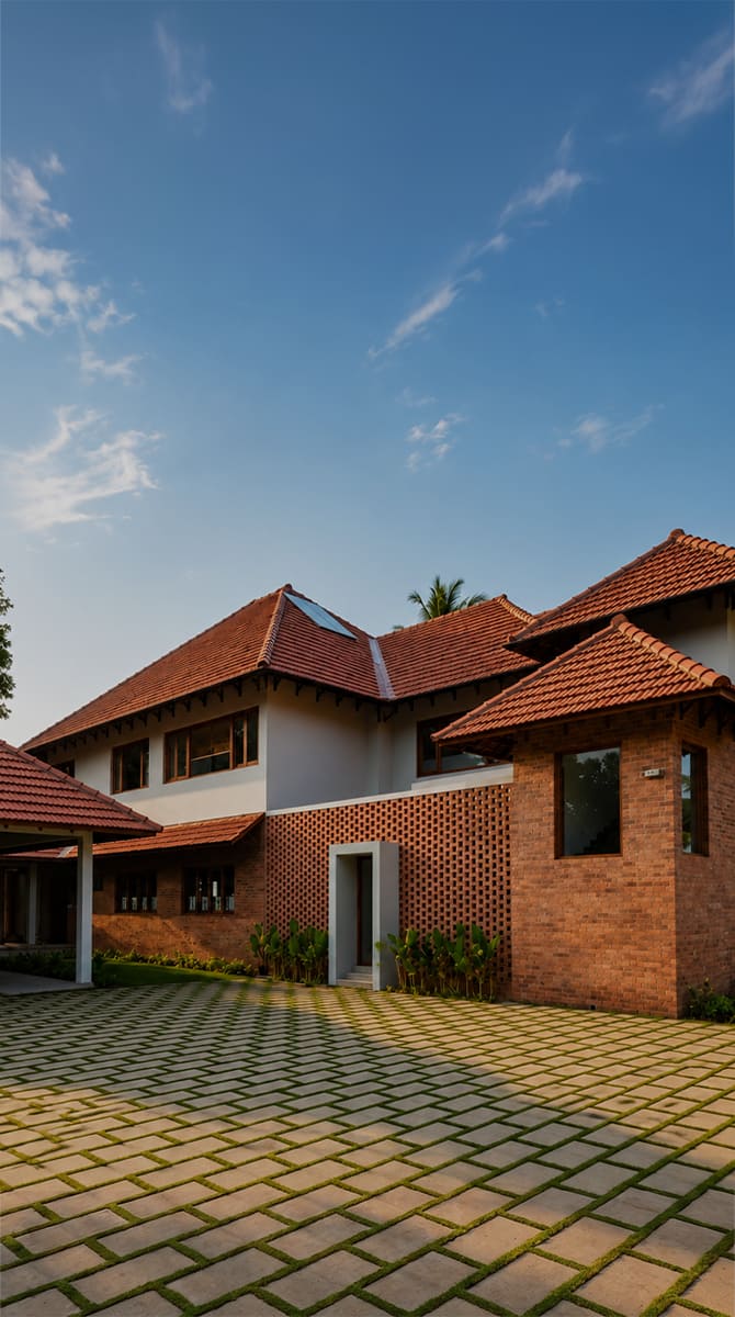 Exposed brick masonry and traditional Kerala roofs blending with lush landscape